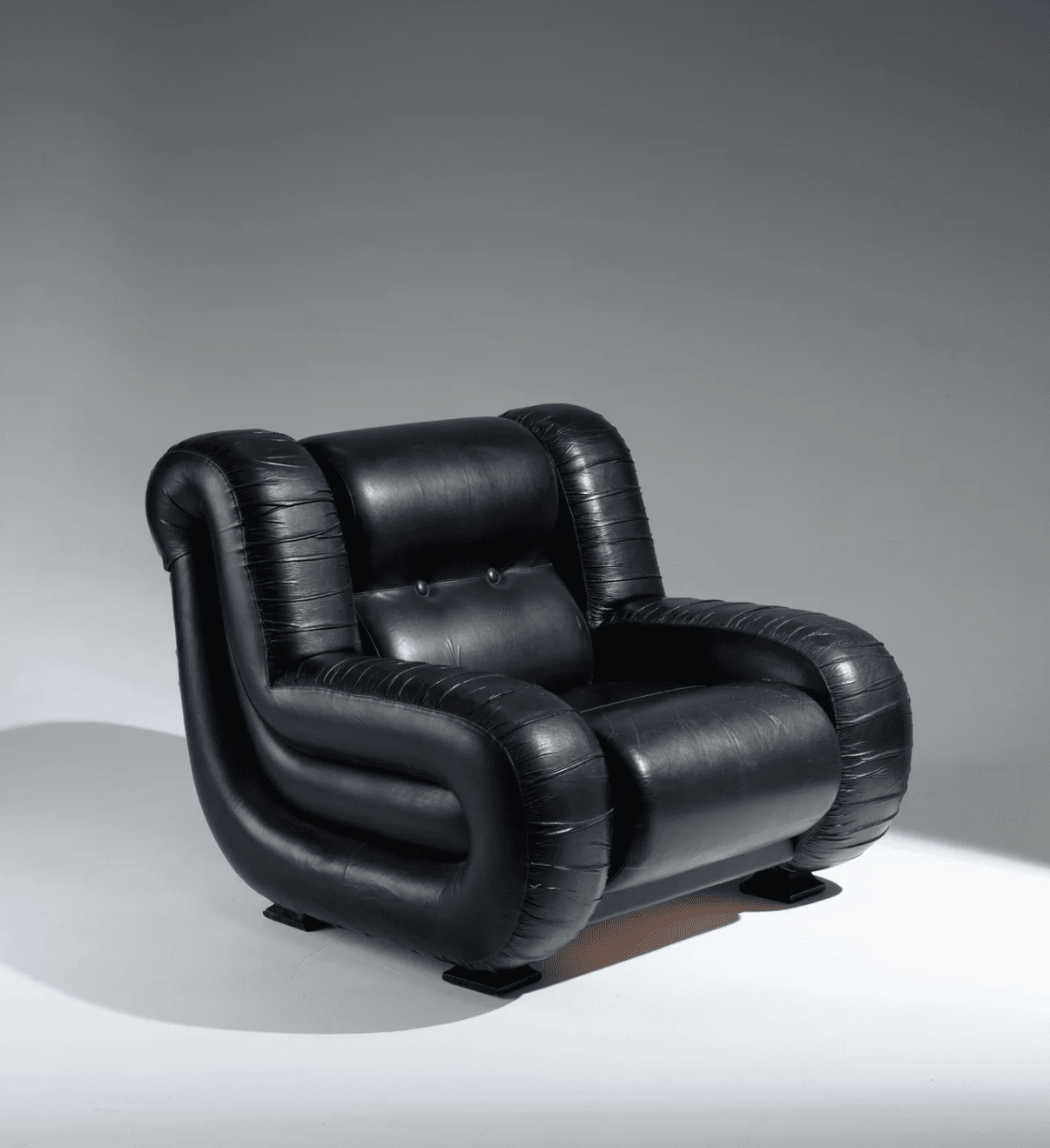 A black leather armchair with a distinctive, puffy, curvilinear design. The armchair features rounded arms and a backrest that appear inflated, with horizontal stitching details creating a ribbed texture on the sides of the arms and the base of the chair. Two dark square feet support the armchair. The seat cushion is tufted with two visible buttons. — 3D model