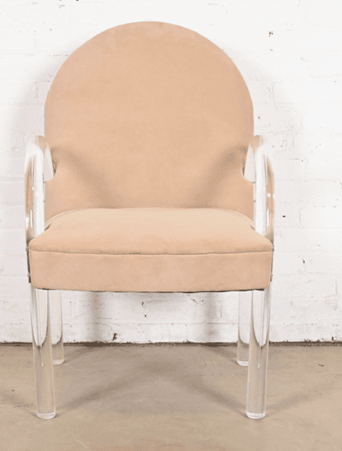 A contemporary armchair with a rounded back and upholstered seat and backrest. The chair features curved armrests and legs constructed from clear acrylic material. The upholstery appears to be a soft, textured fabric. The frame is supported by four cylindrical acrylic legs. — 3D model