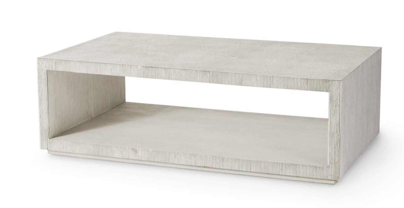 A rectangular coffee table featuring a distinctive textured finish and an integrated open shelf. The table's design is minimalist, forming a clean, box-like silhouette with a recessed base. The light-colored surface exhibits fine vertical striations, lending a tactile quality to its modern aesthetic. — 3D model