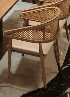 A modern dining or accent armchair featuring a light wood frame, a curved cane webbing backrest, and a beige upholstered seat. — 3D model