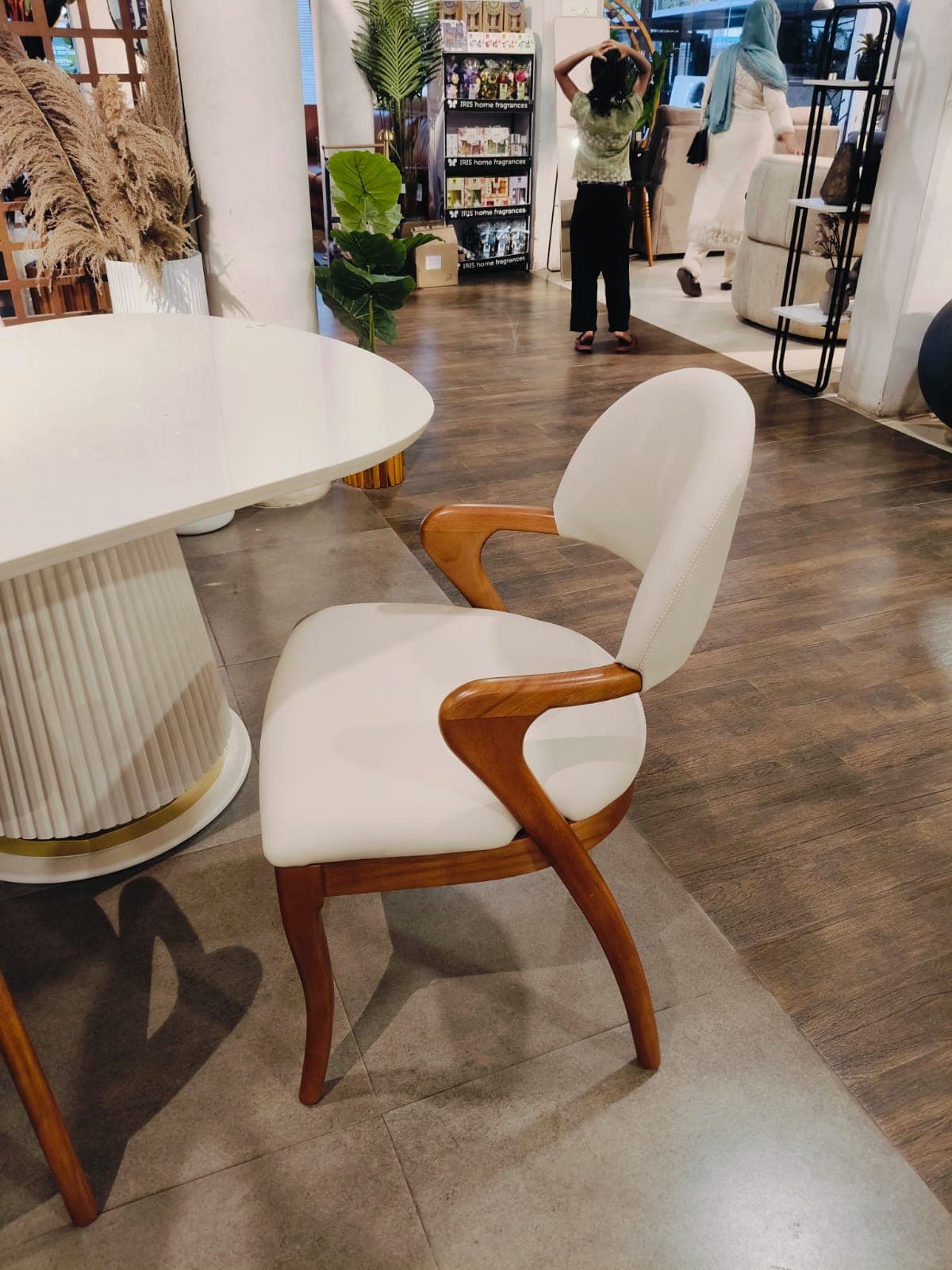 A contemporary dining armchair featuring a solid wood frame with curved elements and light-colored upholstery on the seat and backrest. The design includes integrated armrests and tapered legs. — 3D model
