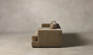 A contemporary sofa with a plush, textured upholstery. It features a low-profile rectangular base, straight arms that curve slightly outwards at the top, and a deep seat cushion. The backrest is divided into two distinct rectangular cushions, providing ample seating space. The overall design is minimalist and modern, with clean lines and a focus on comfort and material. — 3D model