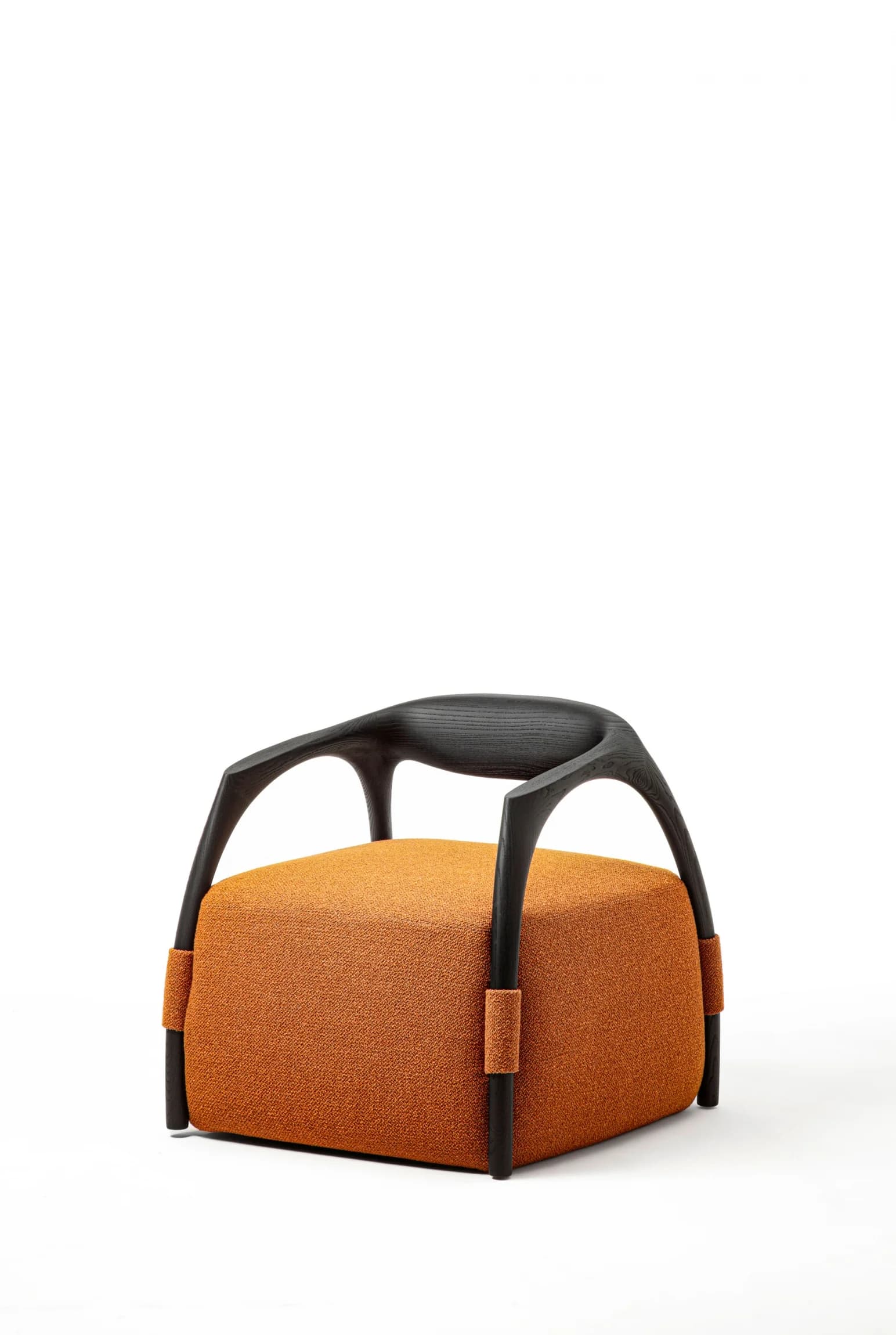 A low-profile modern lounge chair featuring a distinctive dark-stained wooden frame that elegantly wraps around a plush, cube-shaped upholstered seat. The seat is covered in a textured, rust-orange fabric. The wooden frame serves as both armrests and a subtle back support, with its curved, sculptural form creating a unique silhouette. — 3D model