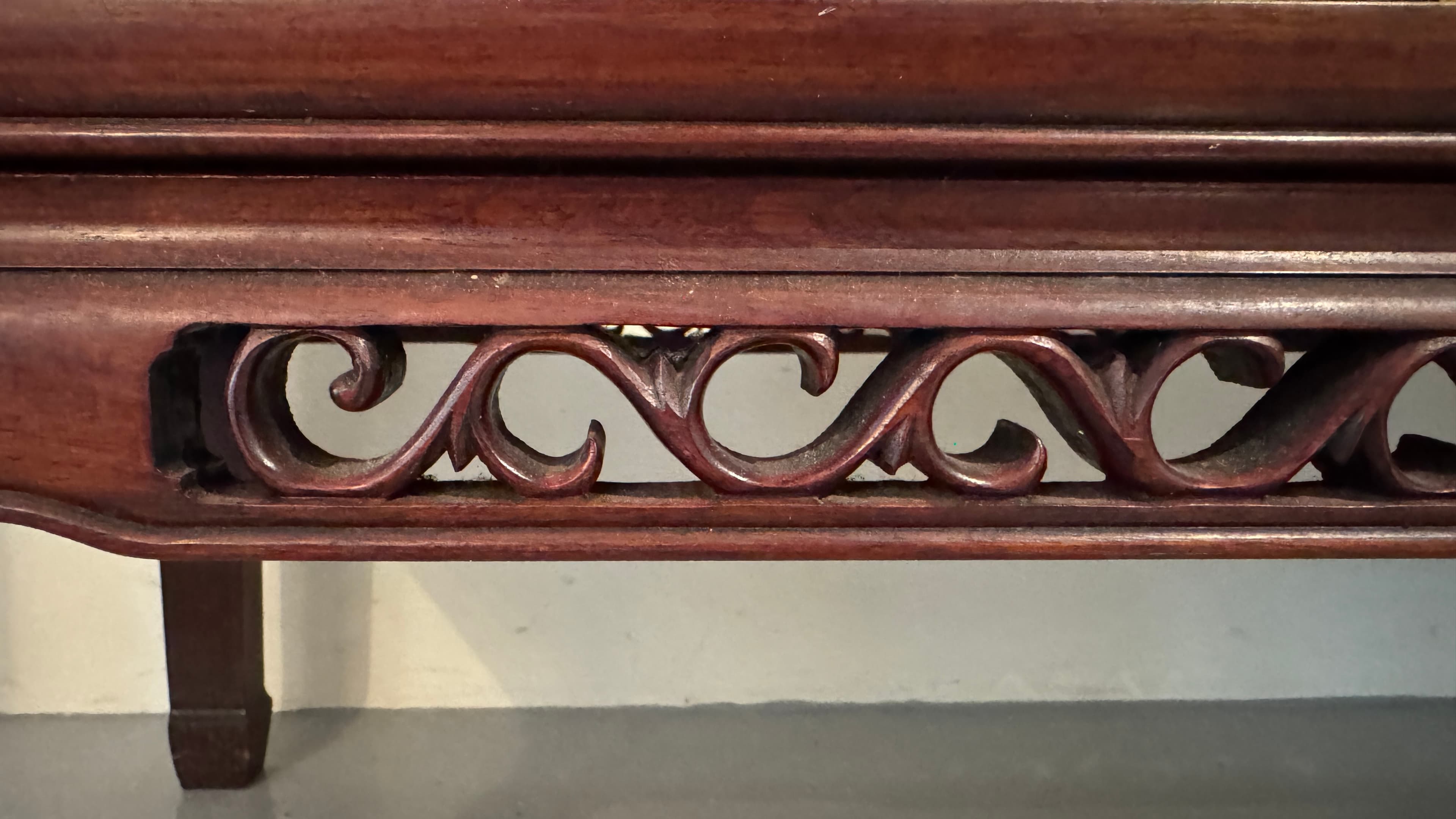 A dark brown, rectangular wall shelf with decorative carved scrolling patterns on its front apron. The shelf has a flat top surface and features a stepped molding detail along the top edge of the front apron. The sides have a slight taper and are also finished in the same dark brown hue. The overall construction appears solid, suggesting a wood material. — 3D model