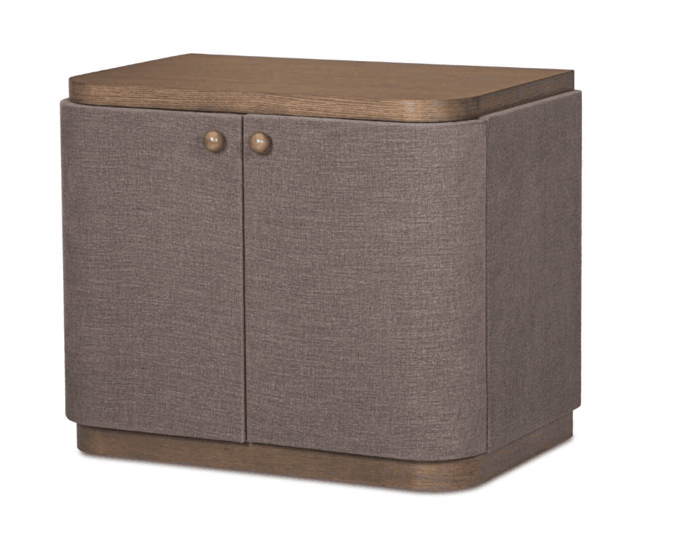 A compact, contemporary storage cabinet featuring a natural wood top and base, with the main body upholstered in a textured, brownish-grey fabric. It has two cabinet doors with small, round metal knobs and gracefully rounded vertical corners. — 3D model