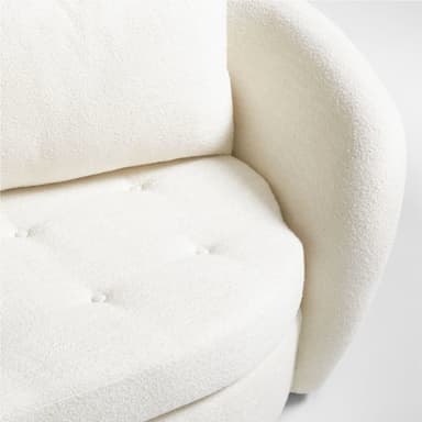 A modern three-seater sofa with a curved silhouette and plush upholstery. It features three loose back cushions and a continuous seat cushion. The arms are rounded and integrated into the overall curved design. The upholstery appears to be a textured fabric, possibly boucle or sherpa, in a light cream color. — 3D model