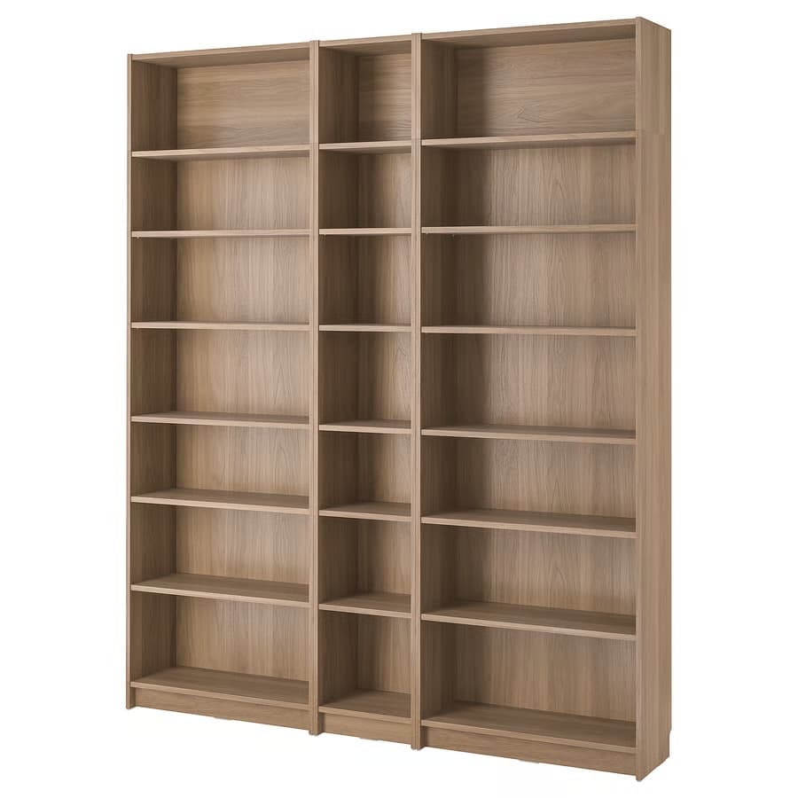 A tall, modular bookcase unit composed of three vertical sections. The leftmost section is wider and has seven shelves, while the two sections to its right are narrower and also feature seven shelves each, with the exception of the rightmost section which has a slightly different shelf spacing in its lower half. The bookcase is constructed from a light-colored wood-effect material with a visible grain pattern. It appears to be free-standing. — 3D model