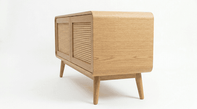 A contemporary, low-profile storage cabinet crafted from light-colored oak wood, featuring smoothly rounded corners on the top, sides, and front panel. It stands on four splayed and tapered legs, presenting a minimalist design with a single large front panel that likely functions as a door for enclosed storage. — 3D model