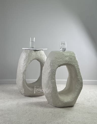 A stool with an abstract, sculptural form. It features a solid, roughly shaped body with a large, irregular opening in the center, suggesting it is designed to be sat upon or used as a small side table. The surface texture is uneven, indicating a material that has been molded or layered. — 3D model