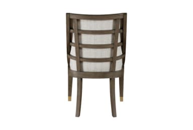 A side profile view of a dining chair. The chair features a dark-stained wooden frame with elegantly curved legs. The backrest is composed of vertical slats and is upholstered, as is the seat, in a light-colored, textured fabric. The front legs have decorative brass caps near the feet. — 3D model