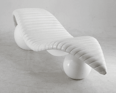 A contemporary white chaise lounge with a distinctive sculptural design. The seating surface is elongated and features horizontal channel tufting, creating a ribbed effect. It is supported by two spherical bases, one positioned towards the front and the other towards the rear, providing an unusual and dynamic stance. The overall form is organic and flowing. — 3D model