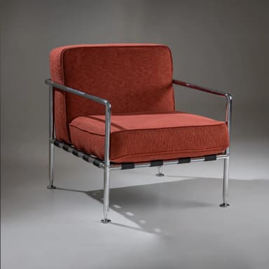 A pair of armchairs with a modern design. Each chair features a polished chrome frame, including the armrests and legs. The seating and back cushions are upholstered in a textured, rust-colored fabric. The seat support appears to be constructed from woven straps. The chairs have a minimalist aesthetic, emphasizing clean lines and industrial materials. — 3D model