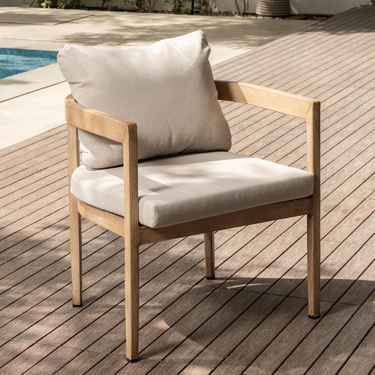 A contemporary armchair featuring a light-toned wooden frame and thick, neutral-colored fabric cushions. The design is minimalist, with straight lines and open armrests, presenting a clean and inviting aesthetic. The chair includes a separate back pillow for added comfort. — 3D model