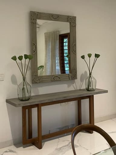 A rectangular wall mirror featuring an intricately carved frame with prominent floral and foliate motifs. The frame has a distressed, light gray or beige finish, giving it a weathered appearance. The mirror surface is clear, reflecting light without distortion. The carving detail is deep and covers the entire frame, including the corners, which are embellished with larger, more complex designs. — 3D model