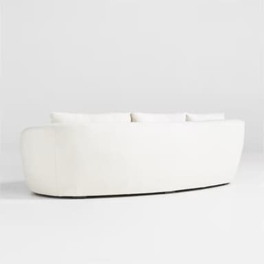 A modern three-seater sofa with a curved silhouette and plush upholstery. It features three loose back cushions and a continuous seat cushion. The arms are rounded and integrated into the overall curved design. The upholstery appears to be a textured fabric, possibly boucle or sherpa, in a light cream color. — 3D model