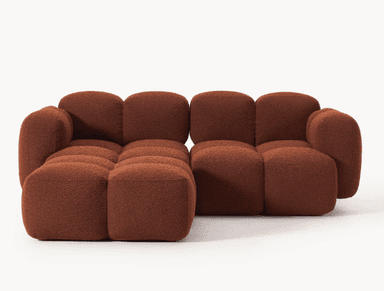 A modular sofa with a rounded, organic silhouette. The sofa is composed of several individual cubic modules that are upholstered in a textured, bouclé fabric. The arrangement suggests a sectional configuration, possibly an L-shape, with distinct seat and backrest sections, and padded armrests. The overall design is characterized by its plush, pillow-like appearance and low profile. — 3D model