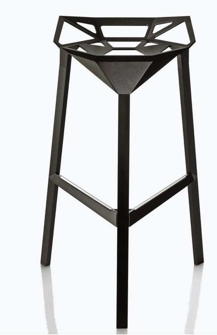 A modern bar stool with a geometric, faceted seat and a matte black finish. It features three angled legs connected by a lower support structure. The seat has an open, angular design with triangular and hexagonal cutouts. — 3D model
