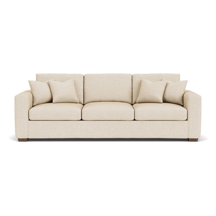 A modern three-seater sofa upholstered in a light, textured fabric, featuring square arms, loose seat and back cushions, and four included throw pillows, all resting on subtle wooden block feet. — 3D model