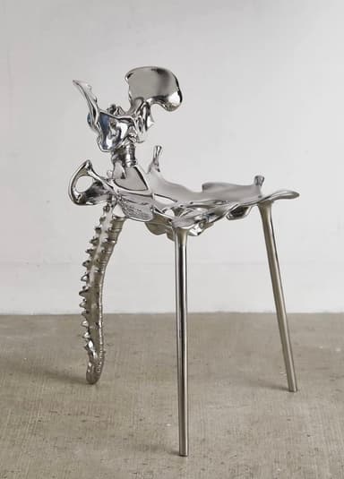 A unique chair with a design inspired by skeletal anatomy. The seat and backrest appear to be sculpted in the form of pelvic bones and a spine, while the legs are slender and metallic. The overall finish is highly reflective, giving it a polished metallic appearance. — 3D model