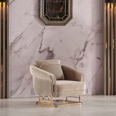 A contemporary armchair featuring soft, light brown velvet upholstery with a distinctive fluted or reeded pattern on its backrest and the outer sides of its curved armrests. The chair is supported by a sleek, rectangular gold-finished metal base. It includes a loose back cushion, also upholstered in velvet, with a contrasting patterned fabric panel and a gold trim detail. — 3D model