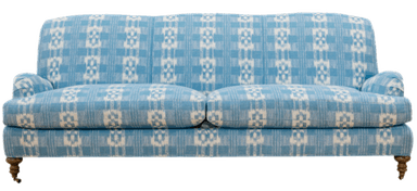 A detailed view of the side and back of a light blue and white patterned sofa. The upholstery features a plaid-like design with interspersed geometric motifs. The sofa has rounded arms and is supported by wooden legs, one of which is visible with turned detailing and a small wheel. — 3D model