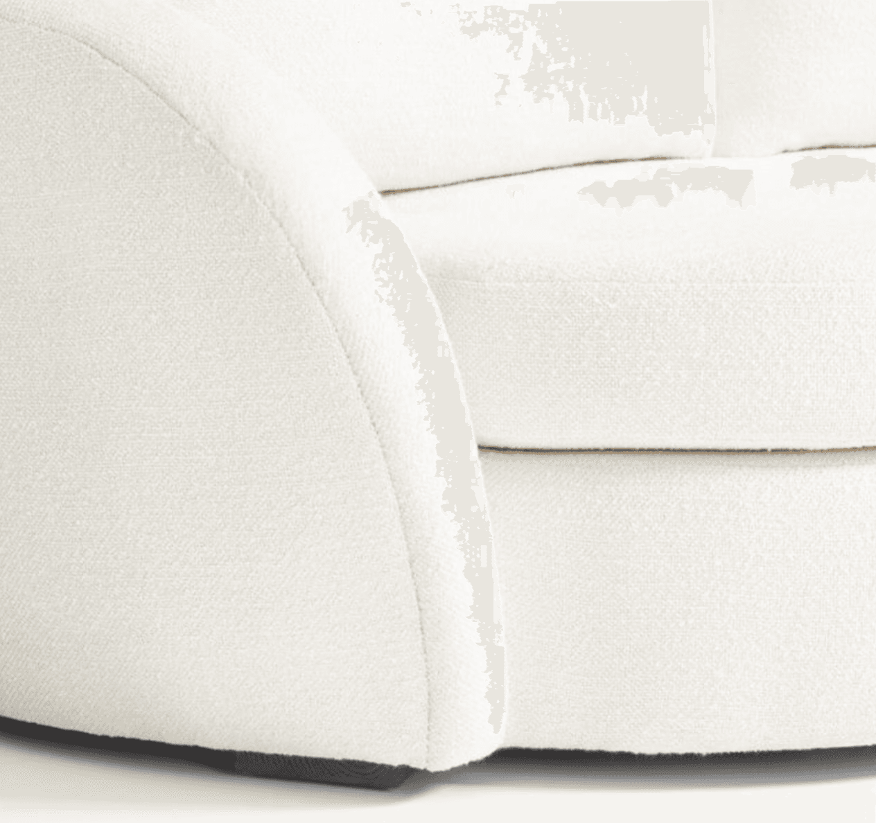 A close-up view of a cream-colored sofa, focusing on the armrest and seat cushions. The upholstery appears to be a textured boucle or similar woven fabric. The armrest has a rounded, curved profile, and the seat cushions are plush with visible stitching. The base of the sofa, where it meets the floor, is partially visible and appears to be a dark wood. — 3D model