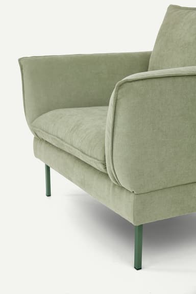 A contemporary upholstered armchair featuring a soft, muted sage green fabric, loose seat and back cushions, and slender, complementary dark green metal legs. — 3D model