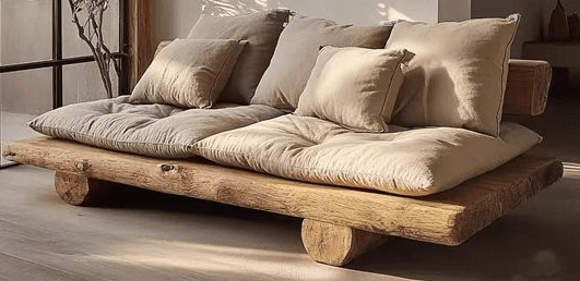 A rustic daybed featuring a natural wood frame made from thick, unfinished logs or planks, supporting thick, light-colored fabric cushions and several throw pillows. — 3D model