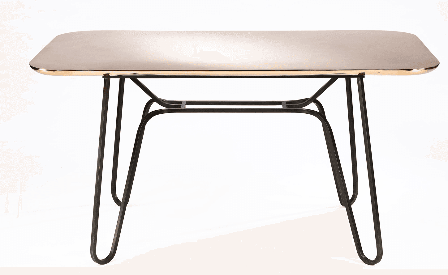 A rectangular dining table with rounded corners. The tabletop has a polished, reflective surface with a warm metallic tone, possibly brass or copper, and a distinct gold-toned edge trim. The base consists of four slender, dark-colored metal legs that splay outwards and are connected by a central, minimalist metal frame. — 3D model