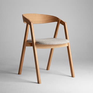 A modern armchair constructed from light-toned wood, featuring a curved backrest that flows into integrated armrests. The seat is an upholstered pad covered in a light grey textured fabric. — 3D model