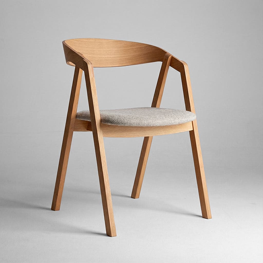 A modern armchair constructed from light-toned wood, featuring a curved backrest that flows into integrated armrests. The seat is an upholstered pad covered in a light grey textured fabric. — 3D model