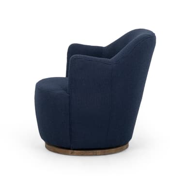 A contemporary armchair upholstered in a textured navy blue fabric. It features a rounded back and integrated armrests that curve gently downwards. The chair is supported by a circular, dark wood swivel base, allowing for 360-degree rotation. The upholstery has a boucle or similar textured finish. — 3D model