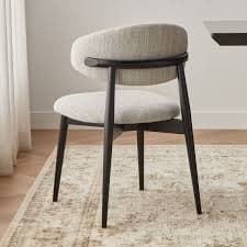 A modern dining chair featuring a light-colored upholstered seat and a curved backrest, supported by dark, tapered wooden legs. — 3D model