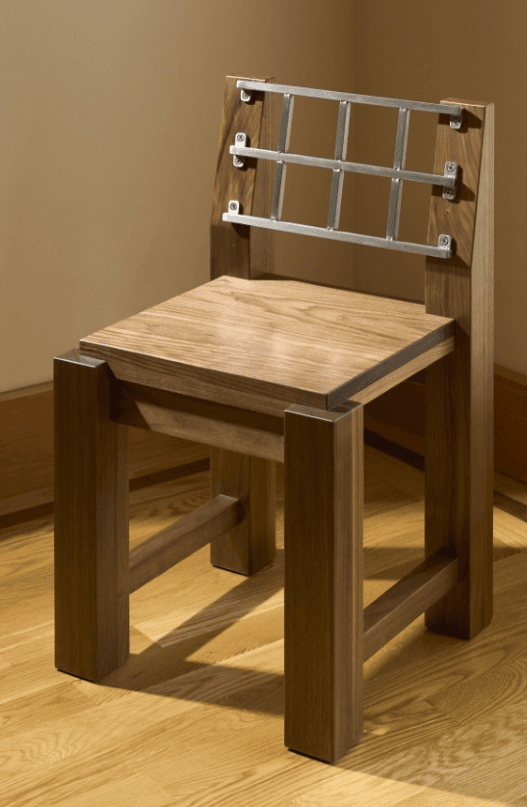 A modern wooden chair with a distinctive metal backrest. The chair features a solid wood seat and legs, with a back composed of vertical wooden uprights supporting a horizontal grid of metal bars. The construction appears sturdy and the design emphasizes geometric shapes. — 3D model