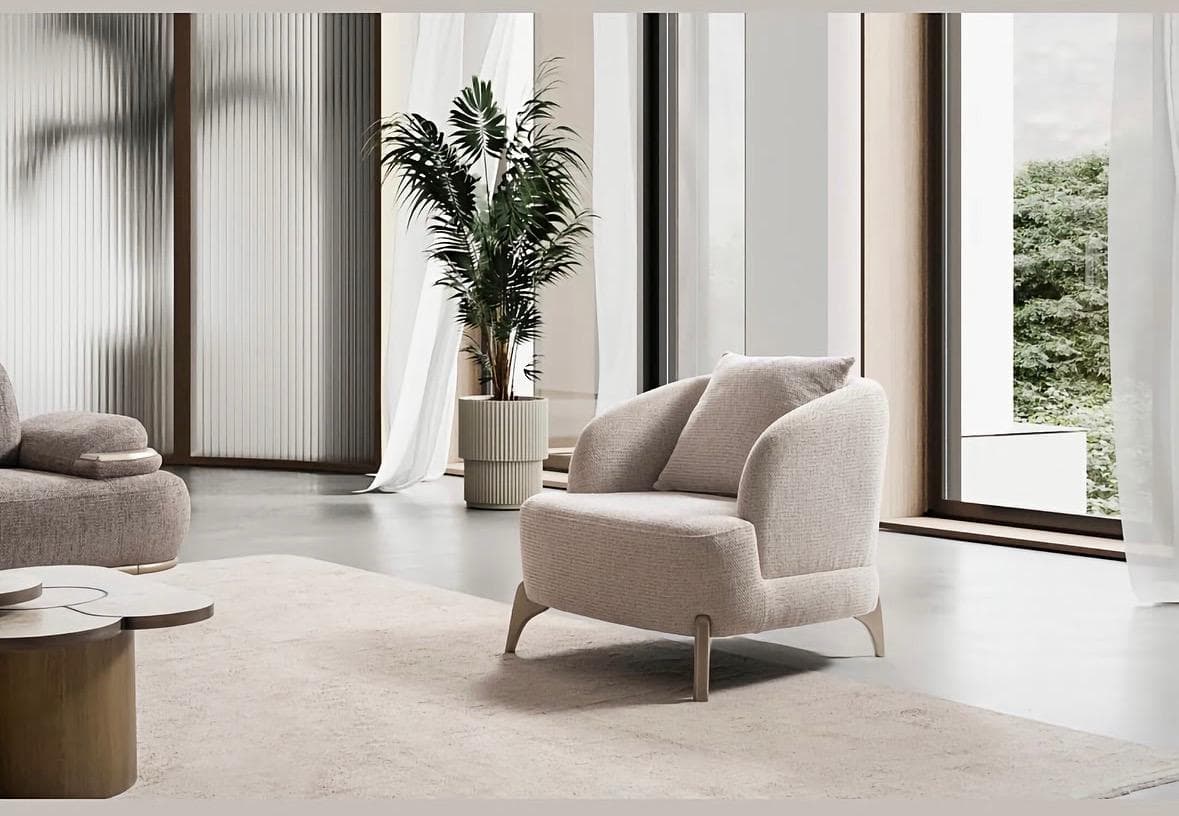 An upholstered armchair with a curved backrest and armrests, featuring a loose back cushion and supported by four tapered, splayed metal legs. — 3D model