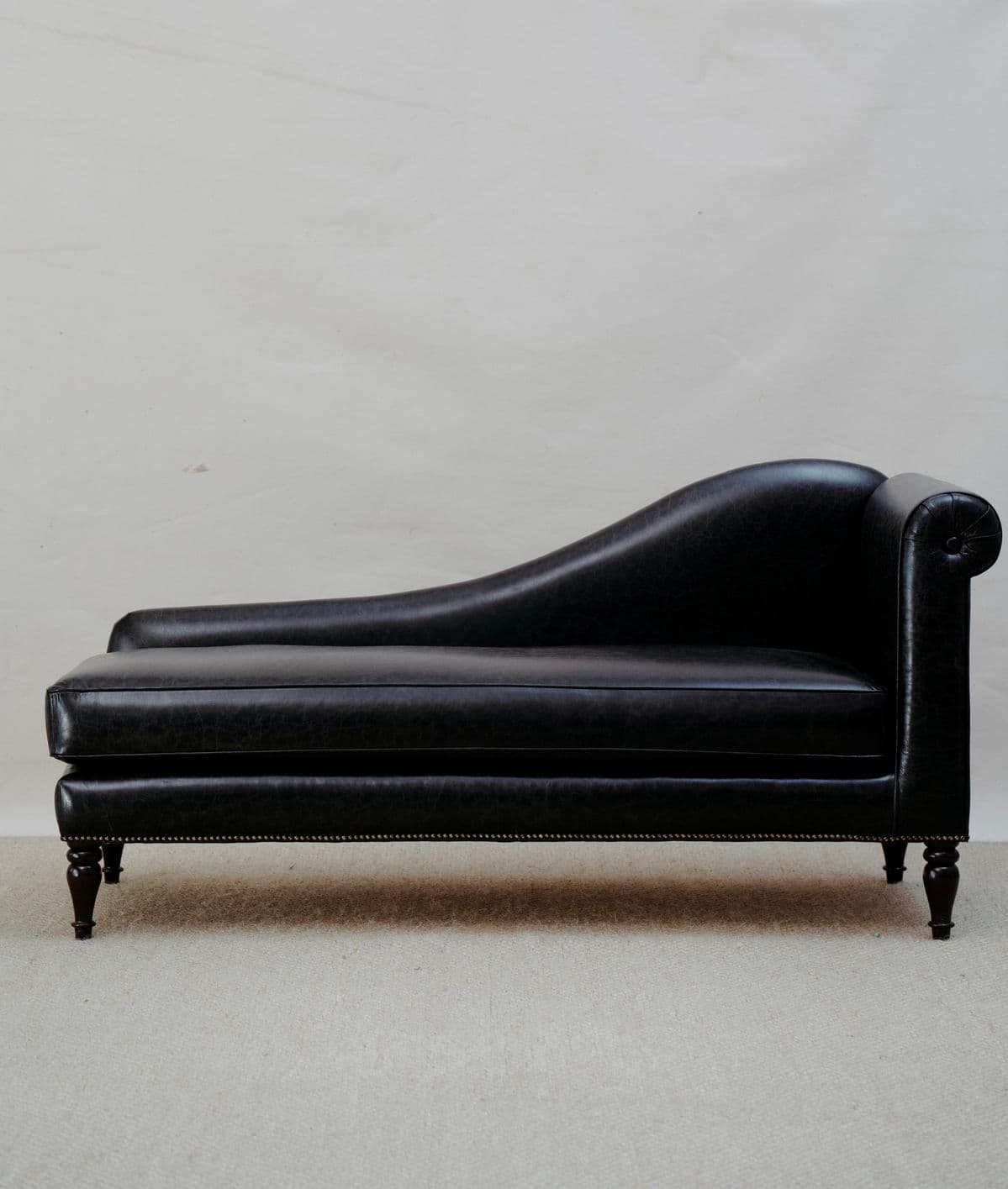 A traditional black leather chaise lounge featuring classic design elements such as a rolled arm, curved backrest, and nailhead trim. — 3D model