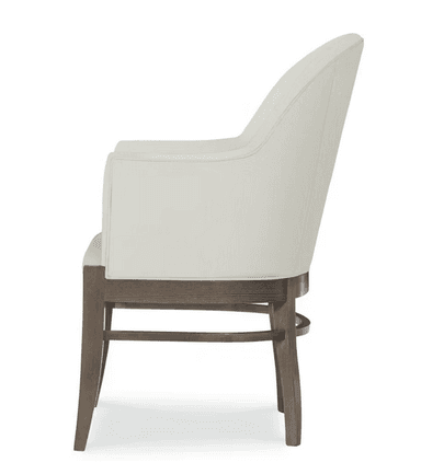 A cream-colored armchair with a high, curved back and upholstered arms. The seat is also upholstered in the same fabric. The frame and legs are made of wood with a weathered, gray-brown finish. The legs have a slightly tapered profile. — 3D model