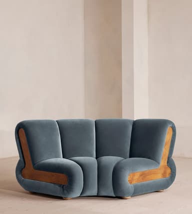 A modern, sculptural two-seater loveseat upholstered in deep blue velvet, featuring distinctive curved burl wood panel accents on its sides. — 3D model
