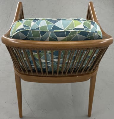 A barrel-back armchair featuring a warm-toned wooden frame, likely teak or oak, with distinctive woven or rope detailing along the arms and backrest. The chair is upholstered with removable seat and back cushions in a textured, multi-tonal green, white, and blue striped fabric. Its design combines elegant curves with a relaxed, tropical-modern aesthetic. — 3D model