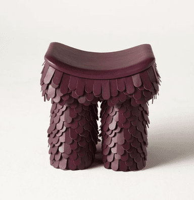 A burgundy, saddle-seat stool featuring a unique, scale-like textured base. The seat is smoothly curved, while the body below is entirely covered in overlapping, rounded panels, resembling feathers or scales. The monochromatic design suggests a modern, sculptural aesthetic. — 3D model