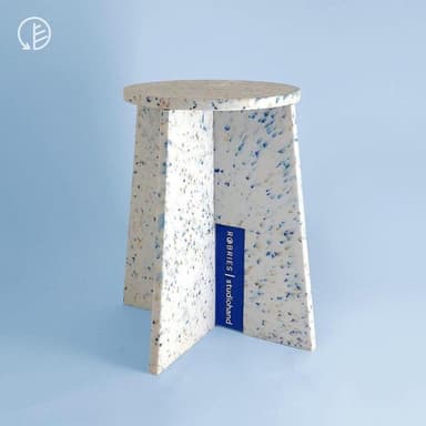 A compact side table featuring a round tabletop and three flat, angled legs, constructed from a light-colored material with multi-colored speckles, resembling recycled plastic or terrazzo. — 3D model