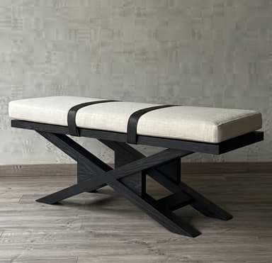 A contemporary bench featuring a rectangular, upholstered cushion secured by decorative dark straps, all supported by a distinctive X-frame base made of dark wood. — 3D model