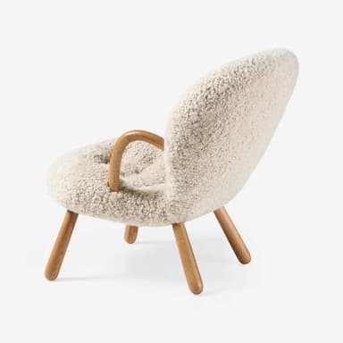 A contemporary lounge chair featuring a fully upholstered body in cream shearling fabric, with integrated curved wooden armrests and splayed wooden legs. — 3D model