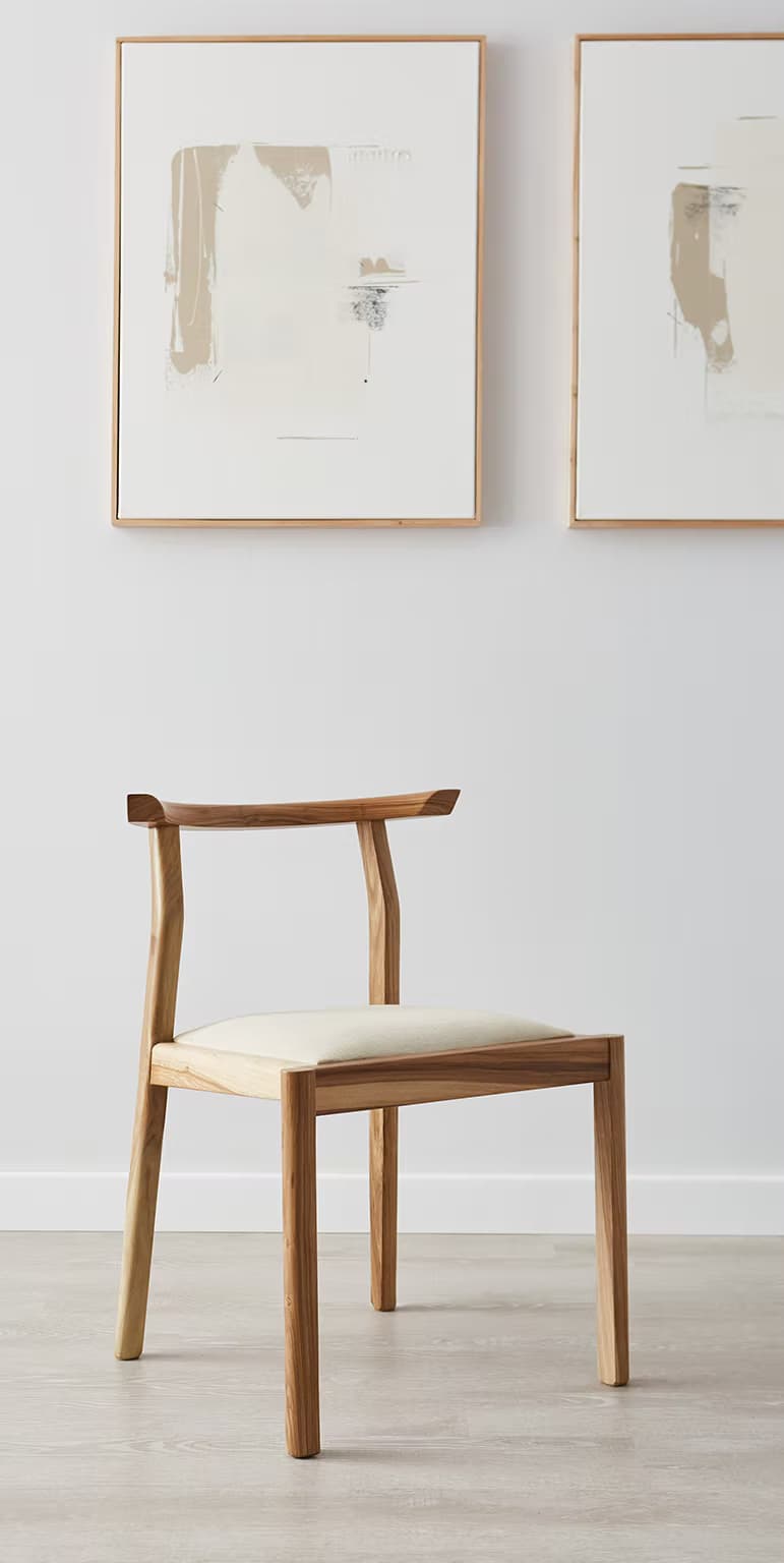 A modern dining chair made from light-colored natural oak wood, featuring a curved backrest that extends into partial armrests. The seat is upholstered in a light, neutral-toned fabric, and the chair stands on four straight wooden legs. — 3D model