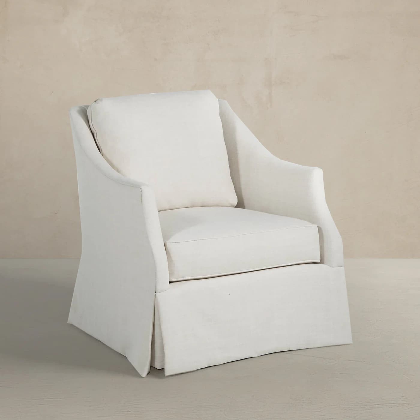 A fully upholstered accent chair featuring a single seat cushion, a loose back cushion, and a distinctive full skirt that extends to the floor, all rendered in a light, neutral-toned fabric. — 3D model