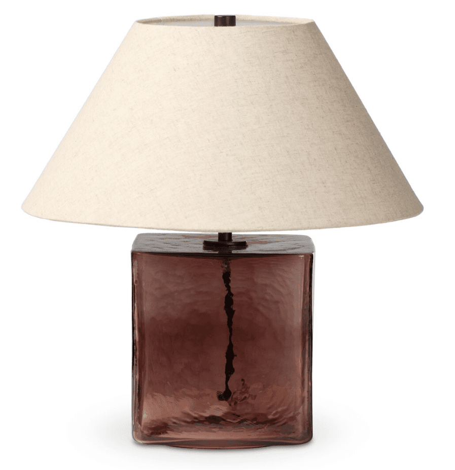 A contemporary table lamp featuring a rectangular prism base made from translucent purple glass with a hammered, organic texture. It is topped with a simple, dark metal finial and a classic tapered cone lampshade in natural beige linen fabric. — 3D model