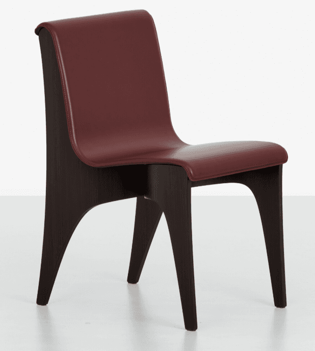 A modern dining chair featuring a curved backrest and seat upholstered in deep red material, contrasted with a dark wood frame. The frame has a distinctive silhouette with flared legs and supporting elements that create an open, sculptural base. The upholstery appears to be leather or a similar high-quality synthetic material, with visible stitching along the edges. The wood frame has a visible grain pattern, suggesting it is either solid wood or a high-quality veneer. — 3D model