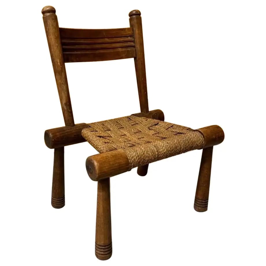 A rustic, low-seated wooden chair featuring a sturdy frame of dark-stained wood and a tightly woven seat made of natural rush or rope. It has a simple backrest composed of two horizontal wooden slats. — 3D model