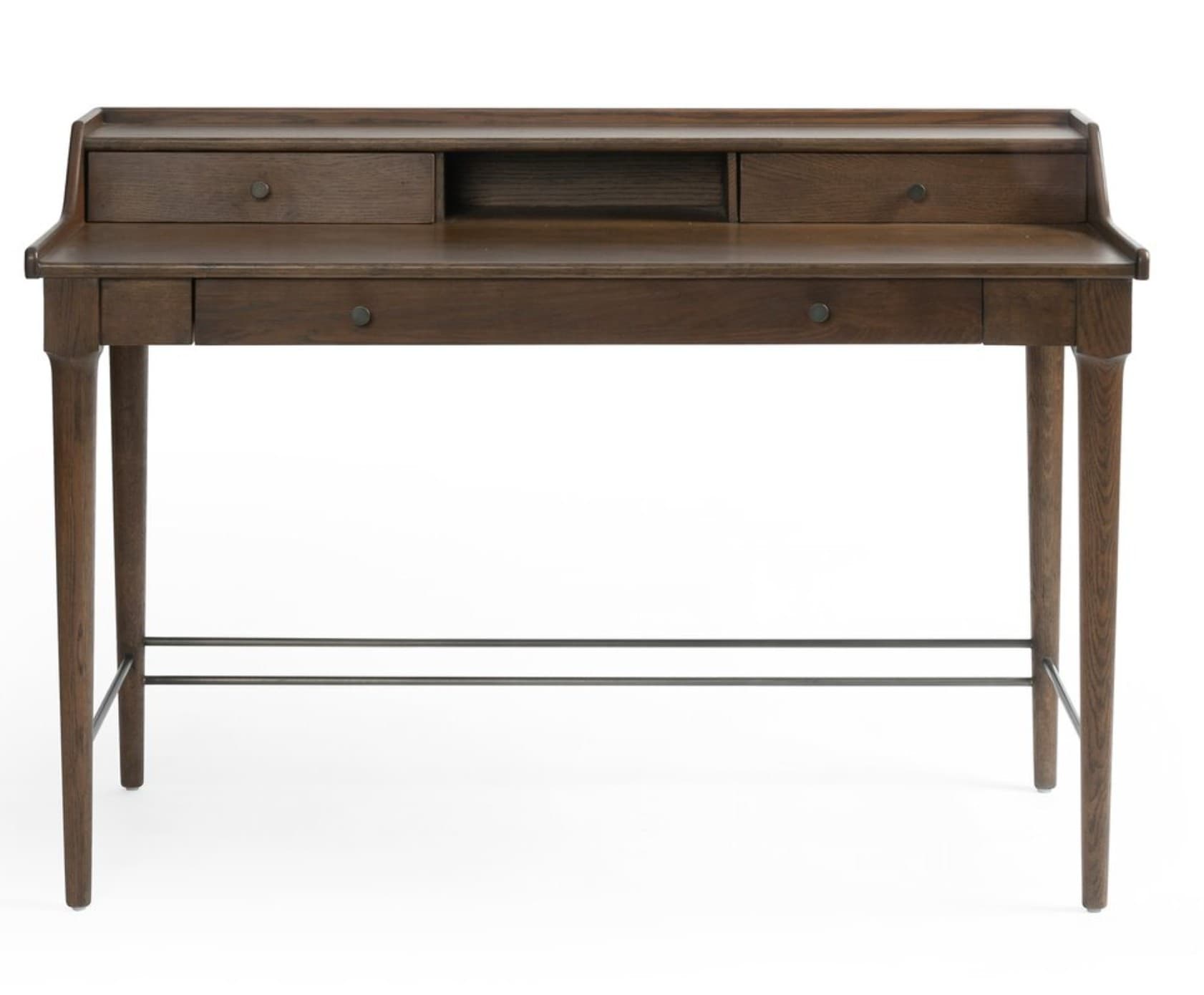 A dark brown wooden writing desk with a minimalist design. It features a raised back panel with three compartments: two drawers on the sides and an open shelf in the center. Below the main surface, there are two additional drawers, one on the left and one on the right. The desk is supported by four tapered legs and includes two horizontal metal bars for added stability and aesthetic detail. — 3D model