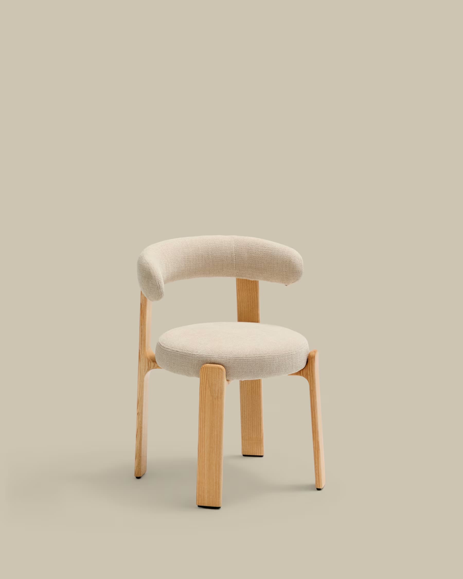 A modern, low-backed dining chair featuring a light-toned wooden frame and light beige upholstered seat and backrest. The backrest is gently curved and extends forward to form integrated armrests. The chair rests on four sturdy, straight wooden legs. — 3D model